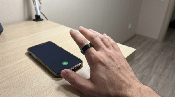 Кольцо WalkerFit на пальце рядом со смартфоном