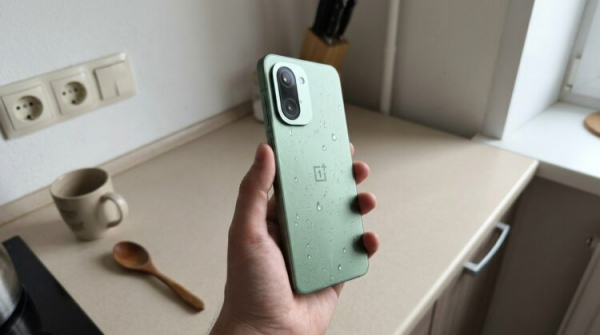 Смартфон OnePlus в руке, капли воды на корпусе