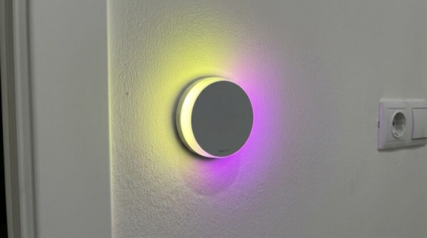 Круглый ночник Yeelight светится жёлто-фиолетовым на стене. Фото.
