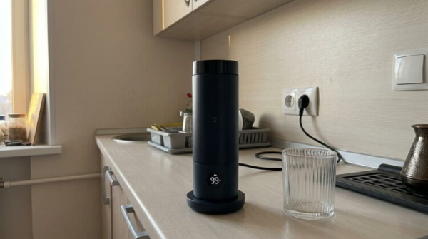Портативный чайник Xiaomi на подставке показывает 99 °C. Фото.