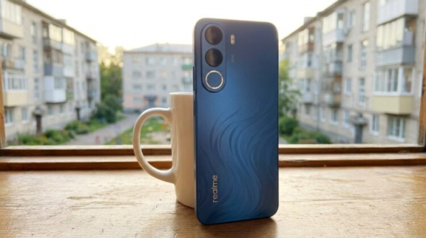 Смартфон Realme на подоконнике рядом с кружкой