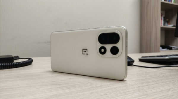 Смартфон OnePlus 15 с тройным блоком камер на столе