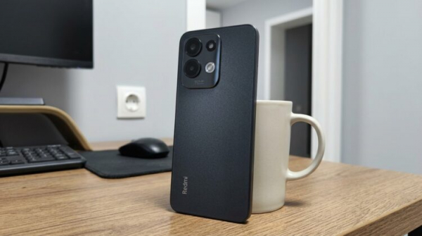 Смартфон Redmi на столе рядом с кружкой