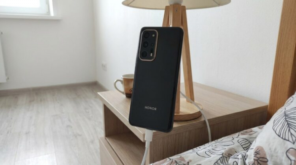 Смартфон Honor на зарядке у прикроватной тумбы